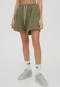Pantalones cortos de mezcla de algodón de color verde oliva con cintura elástica y cordón. Cuenta con dobladillos enrollados y un pequeño logo en la parte delantera.