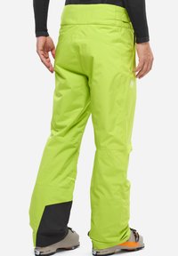 Limgrüne Skihosen mit lockerer Passform, aus wasserdichtem Material, mit schwarzen Akzenten an den Bündchen und einem Logo an der Seite.