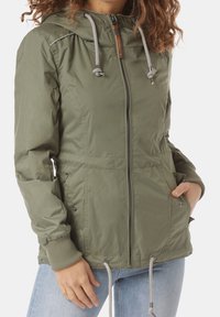 Giacca verde oliva con zip e cappuccio, dettagli con cordini, polsini a coste e tasche laterali; realizzata in materiale leggero.