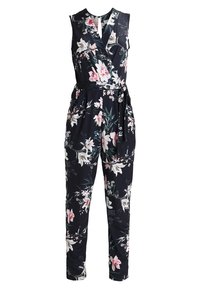 Combinaison noire sans manches à imprimé floral rose et blanc, col en V portefeuille, jambes fuselées, et ceinture assortie en tissu nouée à la taille.