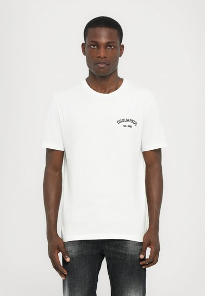 T-shirt en coton blanc avec un col rond et des manches courtes. Présente un texte brodé noir "DSQUARED2 MILANO" sur la zone gauche de la poitrine.