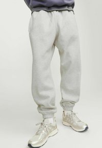Gray sweatpants with elastic waistband and cuffs, featuring a soft, textured fabric. Paired with light-colored athletic shoes.