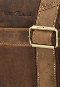 Borsa in pelle marrone con una superficie testurizzata, dotata di una fibbia e cuciture in tonalità dorata. Il marchio "GREEN BURRY" è impresso sulla pelle.