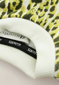 Pullover a fantasia con stampa leopardata gialla e verde, realizzato in tessuto morbido con polsini rigati bianchi e etichetta nera.