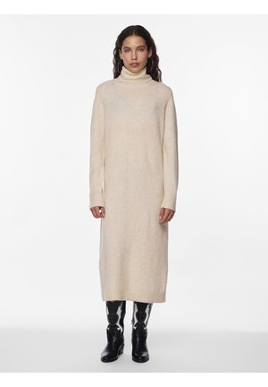 Robe col roulé de couleur crème, confectionnée en matériau tricoté doux, avec des manches longues et une silhouette droite, accompagnée de bottes noires à bouts pointus.