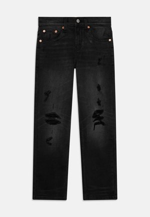 Jean noir coupe droite avec des détails usés sur l'avant des cuisses et des rivets en cuivre sur les poches, posé à plat sur un fond clair.
