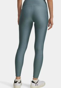 Hochtaillierte Leggings in einer gedämpften Tealfarbe. Hergestellt aus einem glatten, dehnbaren Stoff. Mit einem eleganten, figurschmeichelnden Design und einem minimalistischen Stil.