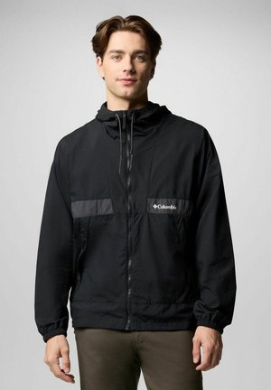 Schwarze Windjacke mit Reißverschluss vorne, Kapuze und elastischen Bündchen. Verfügt über ein graues horizontales Panel und das "Columbia"-Logo auf der Brust.