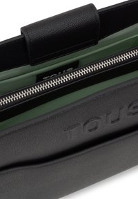 Bolso de cuero negro texturizado con interior verde, con cierre superior de cremallera y logo de la marca en relieve, que muestra un diseño elegante.