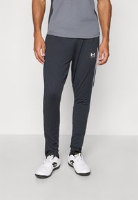 Tumši pelēki sporta bikses ar šauru piegriezumu un baltām sānu svītrām, izgatavotas no viegla, elpojoša auduma. Iekļauta Under Armour logo.