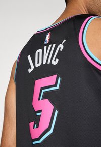 Svart baskettröja med turkosa och rosa detaljer. Har namnet "JOVIĆ" och numret "5" i fet, mönstrad text. NBA-logotypen visas.