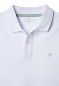 Hvit polo skjorte med teksturert stoff, med krage, to-knapps glidelås og en liten lyseblå brodert logo på brystet.