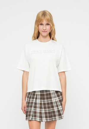 Λευκό βαμβακερό T-shirt με κοντά μανίκια, με το κείμενο "mon chéri". Συνδυάζεται με καρώ πτυχωτή φούστα σε καφέ και κρεμ αποχρώσεις.