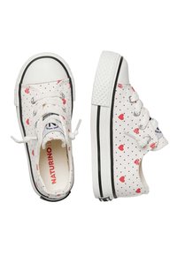 Sneakers bianchi in tela con motivi a cuore rossi e pois neri. Punta arrotondata, suola in gomma bianca e design con lacci. Accenti neri sul bordo della suola.