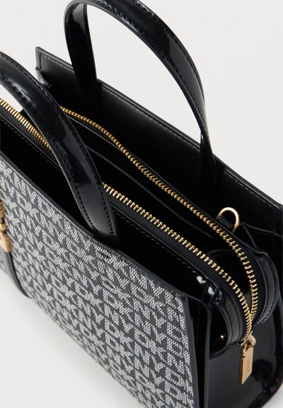 Sac à main noir et gris à motifs avec poignées noires brillantes et une fermeture éclair dorée sur le dessus, présenté ouvert sur un fond uni.