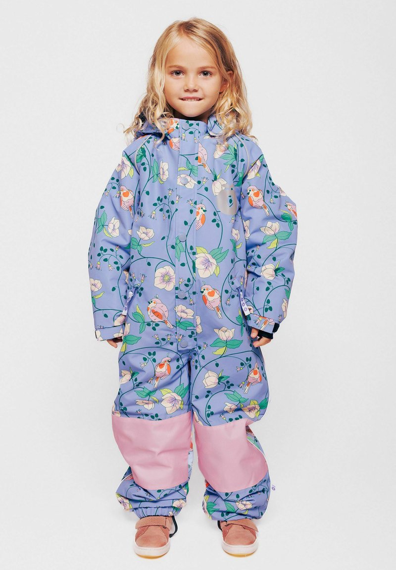 Mono impermeable en púrpura claro con patrones florales y de pájaros; presenta adornos rosas en las piernas, la cremallera frontal y la capucha.