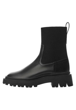 Bottine en cuir noir avec semelle épaisse à crampons et tige en tricot côtelé, dotée d'une languette à l'arrière pour un enfilage facile.