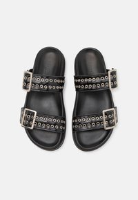 Svarta slidesandaler med dubbla justerbara remmar med silverfärgade öglor och spännen. Släta, strukturerade sulor med en minimalistisk design.