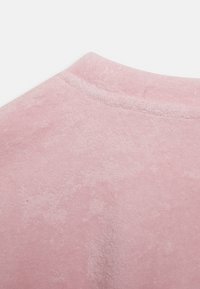 Tecido de sweatshirt rosa claro com uma superfície suave e texturizada, apresentando um decote arredondado e um detalhe de costura subtil ao longo da gola.