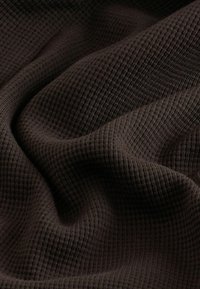 Tela texturizada marrón con un patrón de cuadritos, superficie suave y caída ligera, que muestra profundidad y pliegues en el material.