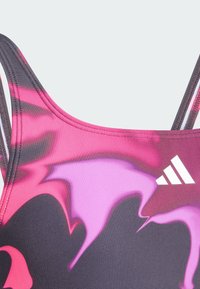 Sporttop met een gradient ontwerp in zwart, roze en paars, voorzien van verstelbare bandjes en een witte logo-accent.