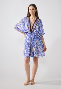 Cubierta de kimono azul translúcido con patrones abstractos en blanco, mangas sueltas y cintura con cordón. Acentuada con un borde trenzado en el escote.