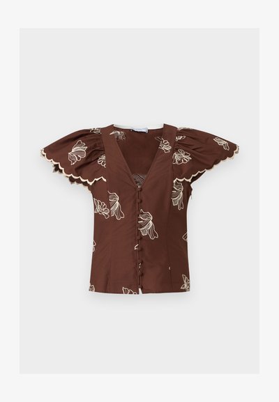 Καφέ μπλούζα με βαθύ V-λαιμόκοψη, κουμπιά καλυμμένα με ύφασμα, φουσκωτά μανίκια πεταλούδας, κυματιστά τελειώματα και λευκή κεντητή ανθοδέσμη.