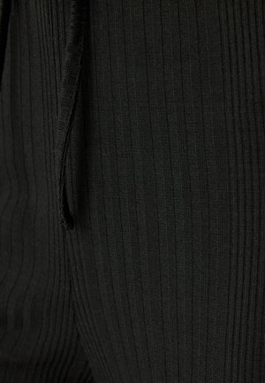 Tessuto a costine nere con strisce verticali, superficie testurizzata e dettaglio con coulisse, che enfatizza la forma e la vestibilità.