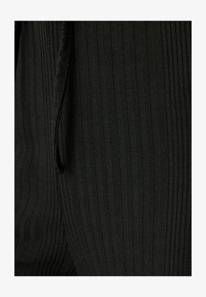 Zwarte ribstof met verticale strepen, een gestructureerd oppervlak en een trekkoorddetail, dat de vorm en pasvorm benadrukt.