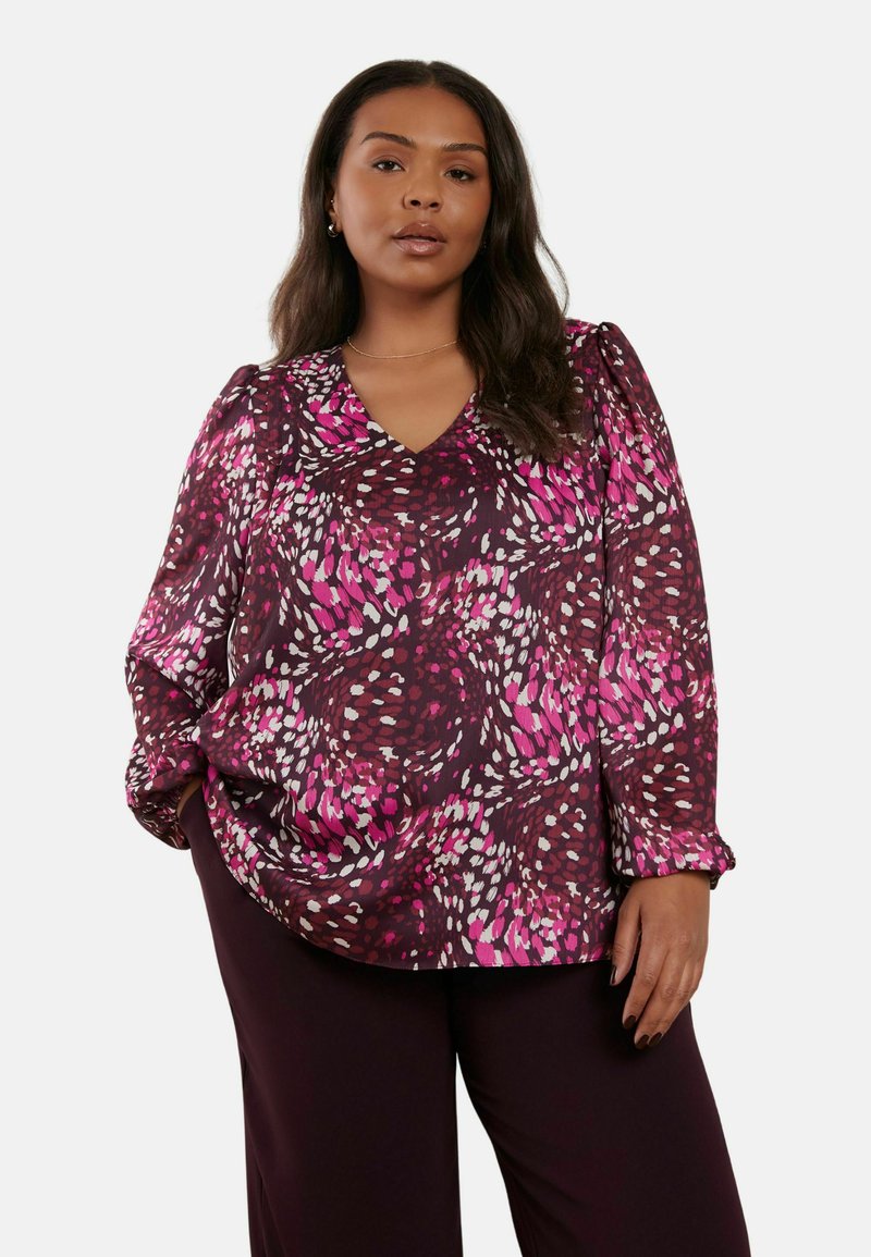 Blusa a maniche lunghe di un profondo bordeaux con un motivo a vortice nei toni del rosa, bianco e viola. Collo a V e tessuto strutturato con maniche arricciate.