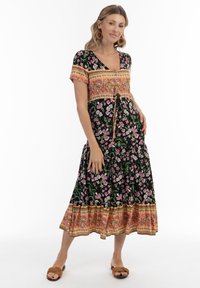 Rochie florală neagră cu mâneci scurte, cu decolteu în V, talie strânsă și accente colorate în nuanțe de portocaliu și roz.