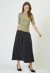 Olíva zöld, rövid ujjú, testhezálló blúz lehetőséggel, fekete, pliszírozott maxi szoknyával. A szoknya A-vonalú fazonnal és sima felülettel rendelkezik.