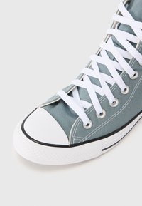 Ανοιχτό μπλε καμβάς ψηλό παπ ούτσι με λευκά κορδόνια, λαστιχένιο καπάκι στα δάχτυλα και μαύρη διακοσμητική γραμμή κατά μήκος της σόλας. Ορατές υφασμάτινες υφές στο πλάι.