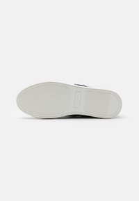 Soletta della scarpa con una superficie in gomma testurizzata, di colore bianco e con un logo in rilievo. Design semplice con una sezione del tacco leggermente sollevata.