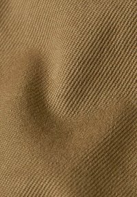 Tessuto marrone con texture che presenta un motivo a trama diagonale, dall'aspetto morbido e con leggere variazioni di tonalità e profondità.