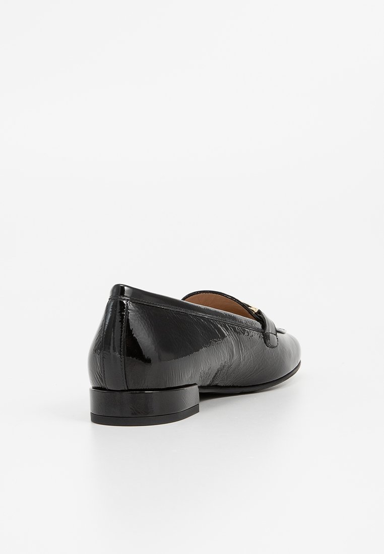 Svart läder slip-on sko med en liten klack, med en strukturerad yta och en dekorativ rosettdetalj framtill.