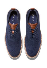 Námořnické pletené tenisky s texturovaným svrškem, lehkou gumovou podrážkou a hnědými koženými akcenty na patě a jazyku.