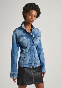 Light blue denim jacket with long sleeves, front buttons, and two chest pockets, paired with a black leather skirt featuring a front zipper.