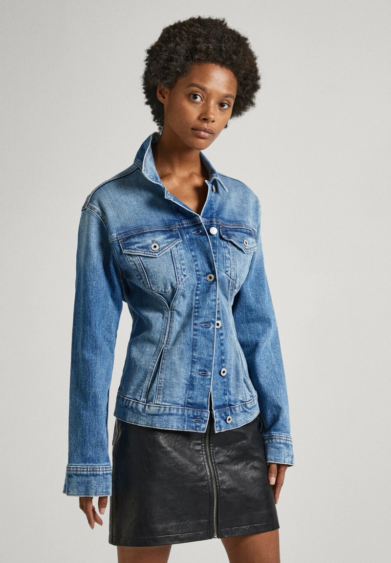 Light blue denim jacket with long sleeves, front buttons, and two chest pockets, paired with a black leather skirt featuring a front zipper.