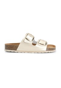 Sandalo a scivolo con due fibbie in materiale sintetico oro metallizzato. Caratterizzato da una soletta in sughero e suola in gomma texturizzata. Profilo piatto con punta aperta.