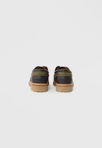Chaussures en cuir avec un dessus noir et des accents vert olive ; comportent une semelle beige et des détails de couture rouge double.