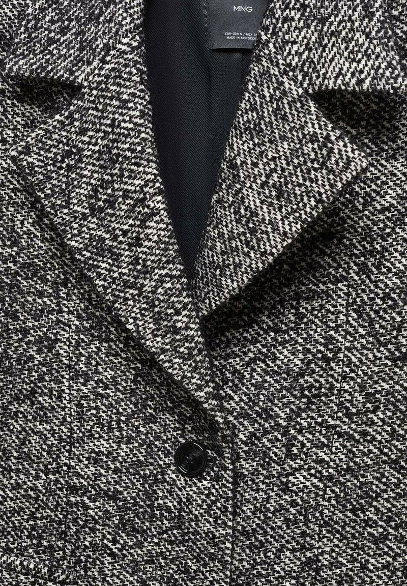 Blazer a motivo houndstooth grigio e nero con colletto a rever, chiusura con un singolo bottone nero e fodera interna liscia.