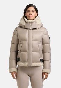 Puffjacke in hellem Beige mit hohem Kragen und Fellfutter. Verfügt über ein gestepptes Design, kontrastierende Beigefarbene Fellbündchen und Saum sowie seitliche Taschen.