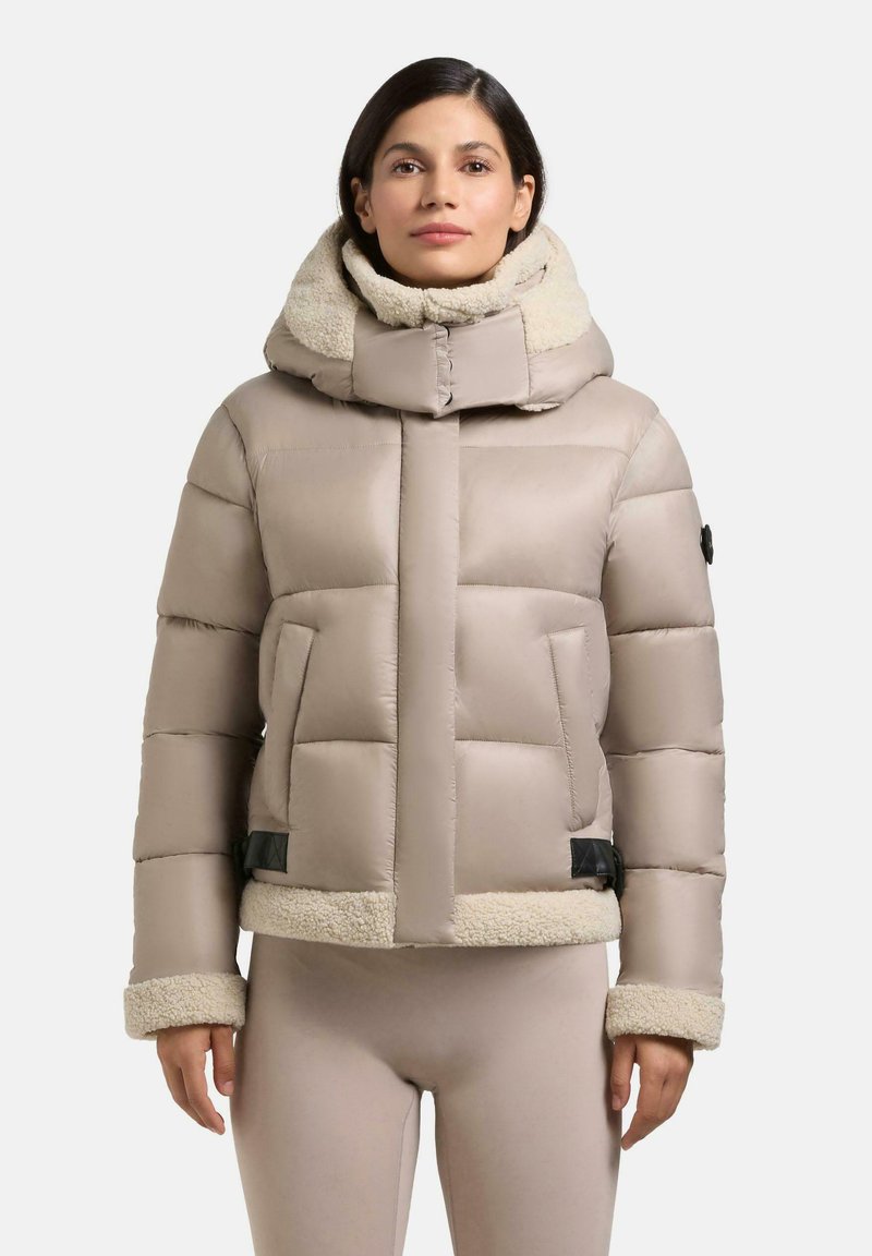 Puffjacke in hellem Beige mit hohem Kragen und Fellfutter. Verfügt über ein gestepptes Design, kontrastierende Beigefarbene Fellbündchen und Saum sowie seitliche Taschen.