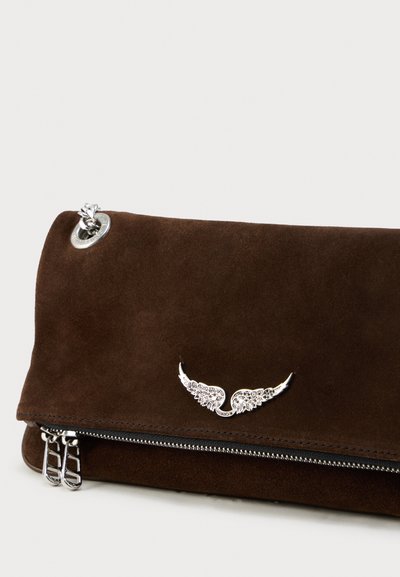 Barna velúr banán táska ezüst szárny díszítéssel, cipzáras záródással és kör alakú fémlyukkal. Puha tapintású, téglalap alakú.