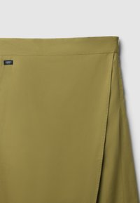 Gonna verde khaki con una texture liscia, caratterizzata da una vita alta e chiusura con zip laterale. Etichetta visibile sulla vita.