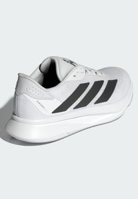 Weißer Laufschuh mit Obermaterial aus Netzgewebe, schwarzem Dreistreifen-Design und leichter Sohle. Verfügt über einen gepolsterten Schaft und texturierte Akzente.