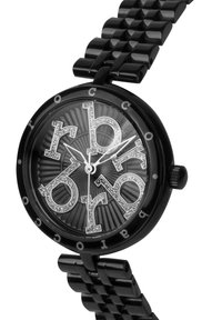 Svart klocka med en glansig plastrem och en rund urtavla. Urtavlan har stora silverfärgade bokstäver och en subtil radial textur för djup.