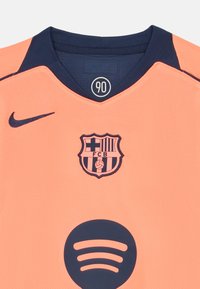 Nike dres svijetlo narančaste boje s tamnoplavim ovratnikom. Ima klubsku oznaku Barcelone i Spotify logo u tamnoplavoj boji. Tekstizirana, prozračna tkanina.