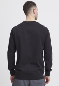 Felpa nera a girocollo con maniche lunghe, realizzata in morbido misto cotone, con orlo e polsini a costine, design semplice e stile minimalista.